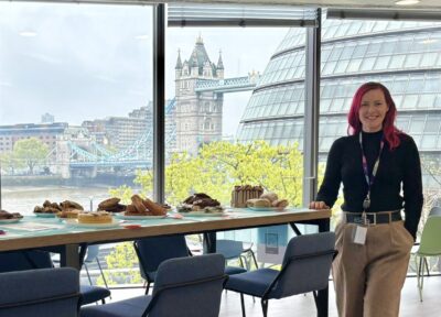 A Southeastern employee at a Railway Children charity bake sale in an office setting with cakes displayed on a high table.