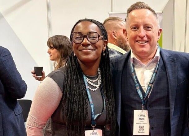 A young female and older man smiling to camera at UK Rail conference 2026