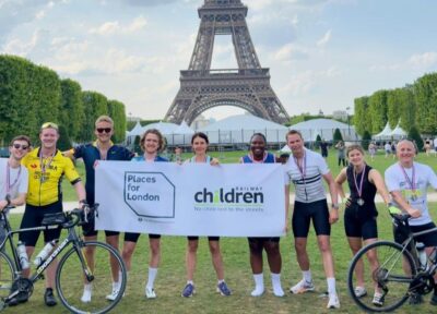 Cyclists holding a Railway Children banner near the Eiffel Tower during a charity bike ride.
