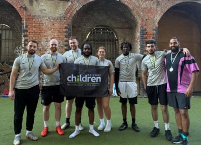Football team holding a Railway Children banner with medals after a charity match.