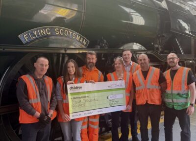 Railway workers presenting a £4,000 donation cheque to Railway Children in front of the Flying Scotsman.