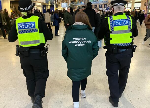 Youth Outreach Worker walking through London Waterloo Station alongside British Transport Police officers during patrol.