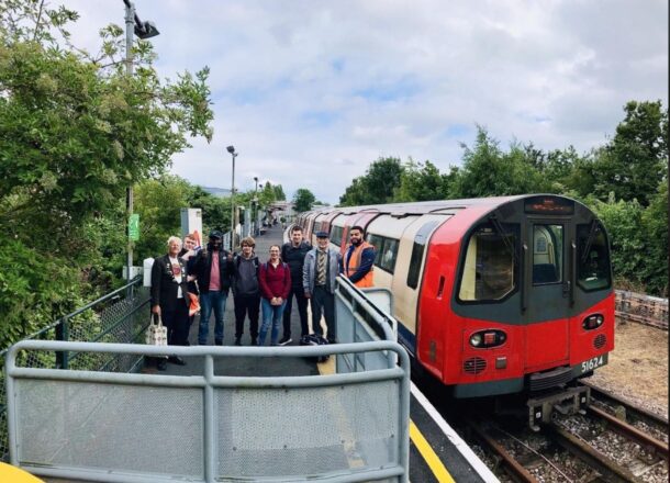A group of people stood on a railway platform next to a red train.