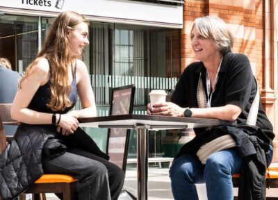 A young person sat with a Railway Children project worker at a train station in the UK.