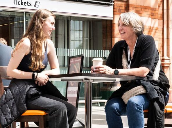 A young person sat with a Railway Children project worker at a train station in the UK.