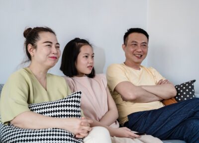 A family of three sat on the sofa in their home talking.