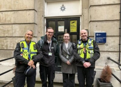 Railway Children staff stood with British Transport Police officers in front of a British Transport Police building in the UK.