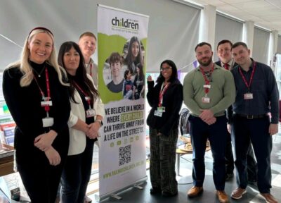 Rail industry colleagues at a form next to a branded banner with community engagement worker Uzma.