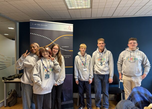 Railway Children youth ambassadors posing at a conference wearing matching grey Youth Platform branded hoodies.