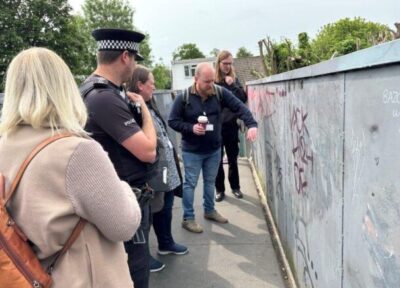 A member of Railway Children staff pointing at some graffiti on the wall of a bridge with various members of the rail industry.