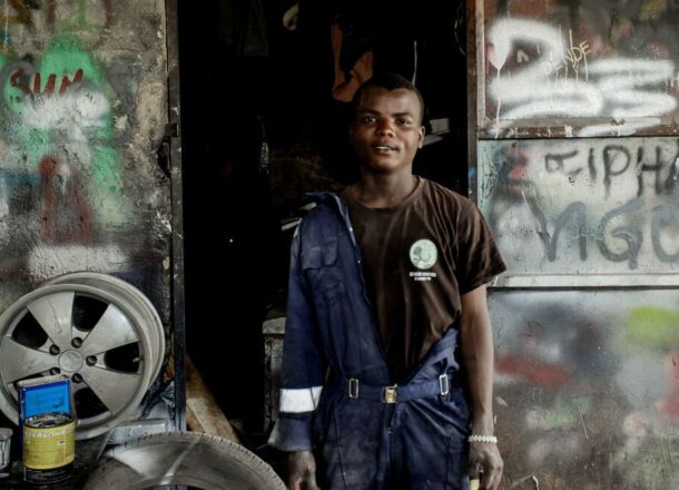 A young mechanic stood in a doorway with graffiti on the walls.