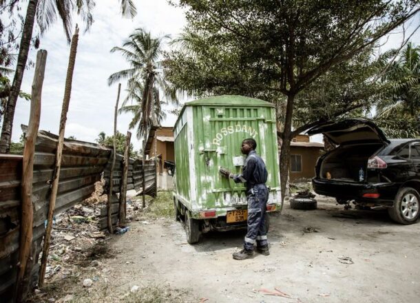Young person in mechanic overalls working on a green vehicle in a vehicle repair yard in Dar es Salaam, Tanzania, using skills gained through vocational training.