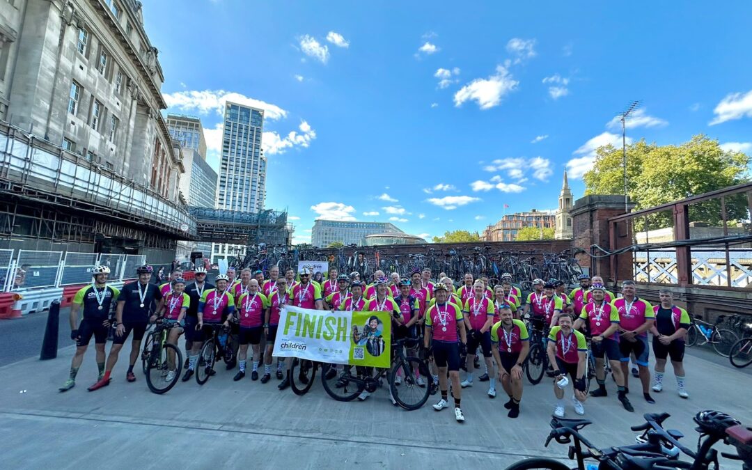 Ride the Route 2026 cyclists celebrate at the finish line with medals, bikes and a Railway Children finish banner after completing the charity cycling challenge.