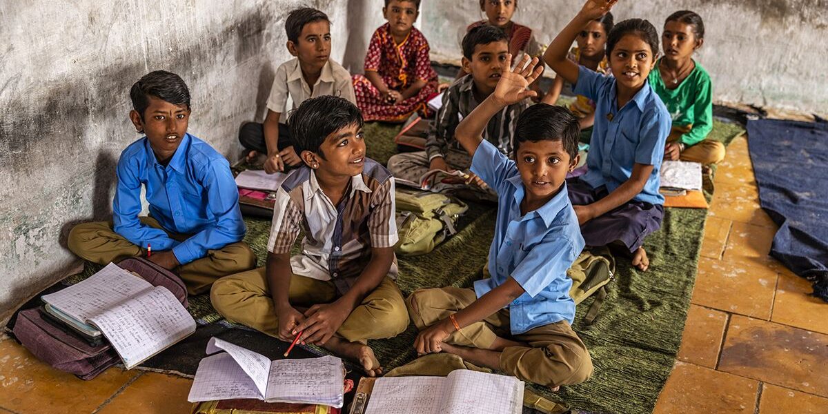 Students attending a classroom lesson and raising hands to participate, supporting education programmes that improve learning opportunities