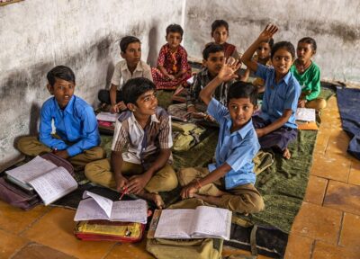 Students attending a classroom lesson and raising hands to participate, supporting education programmes that improve learning opportunities