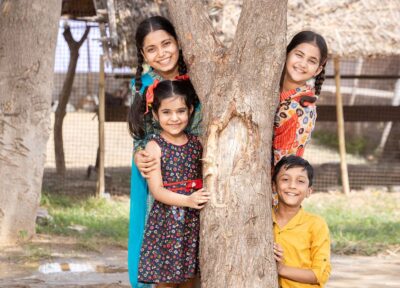 Teacher and children in a local community environment benefiting from programmes that support education, health and wellbeing.