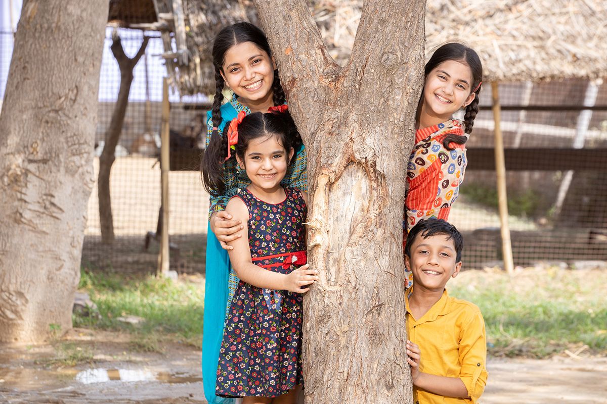 Teacher and children in a local community environment benefiting from programmes that support education, health and wellbeing.