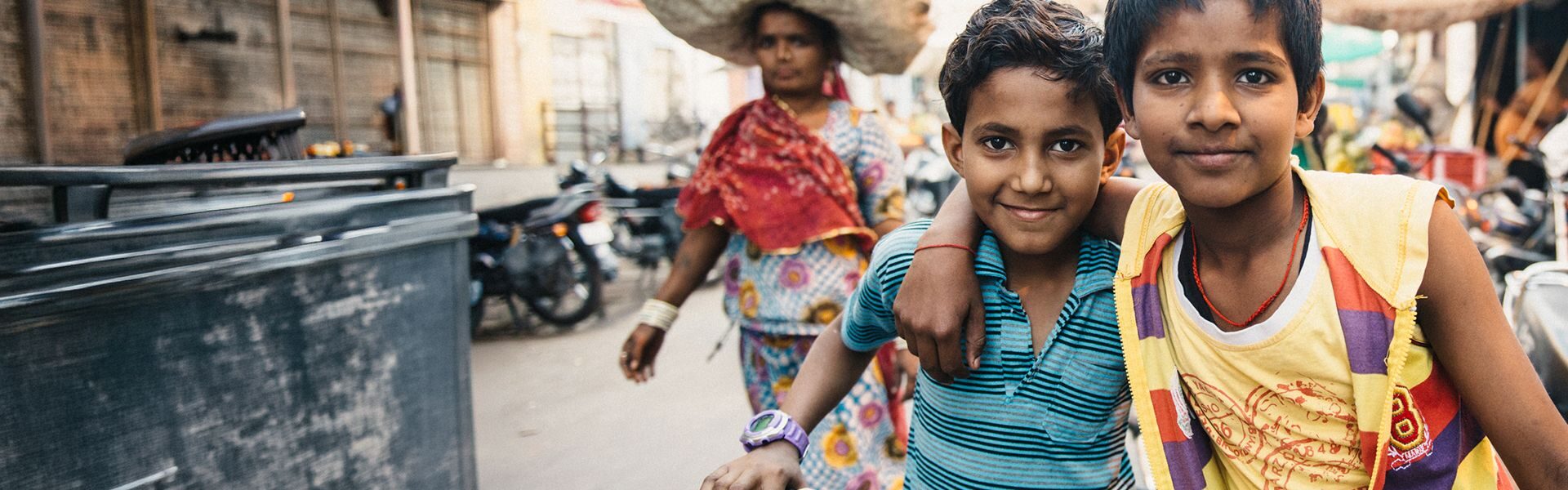 Two children standing with a bicycle in an urban community, highlighting the impact of children's charity programmes supporting vulnerable young people