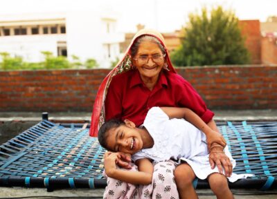 A young girl playing with her grandmother lying on her lap and smiling.